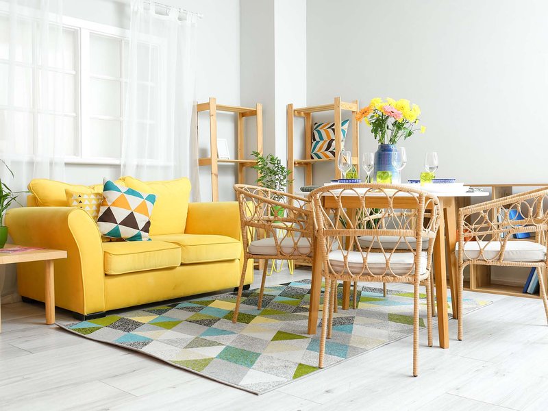 yellow couch and brown chairs and table on a patterned rug in living room with white hardwood floor from Stoller Floors in Orrville, OH